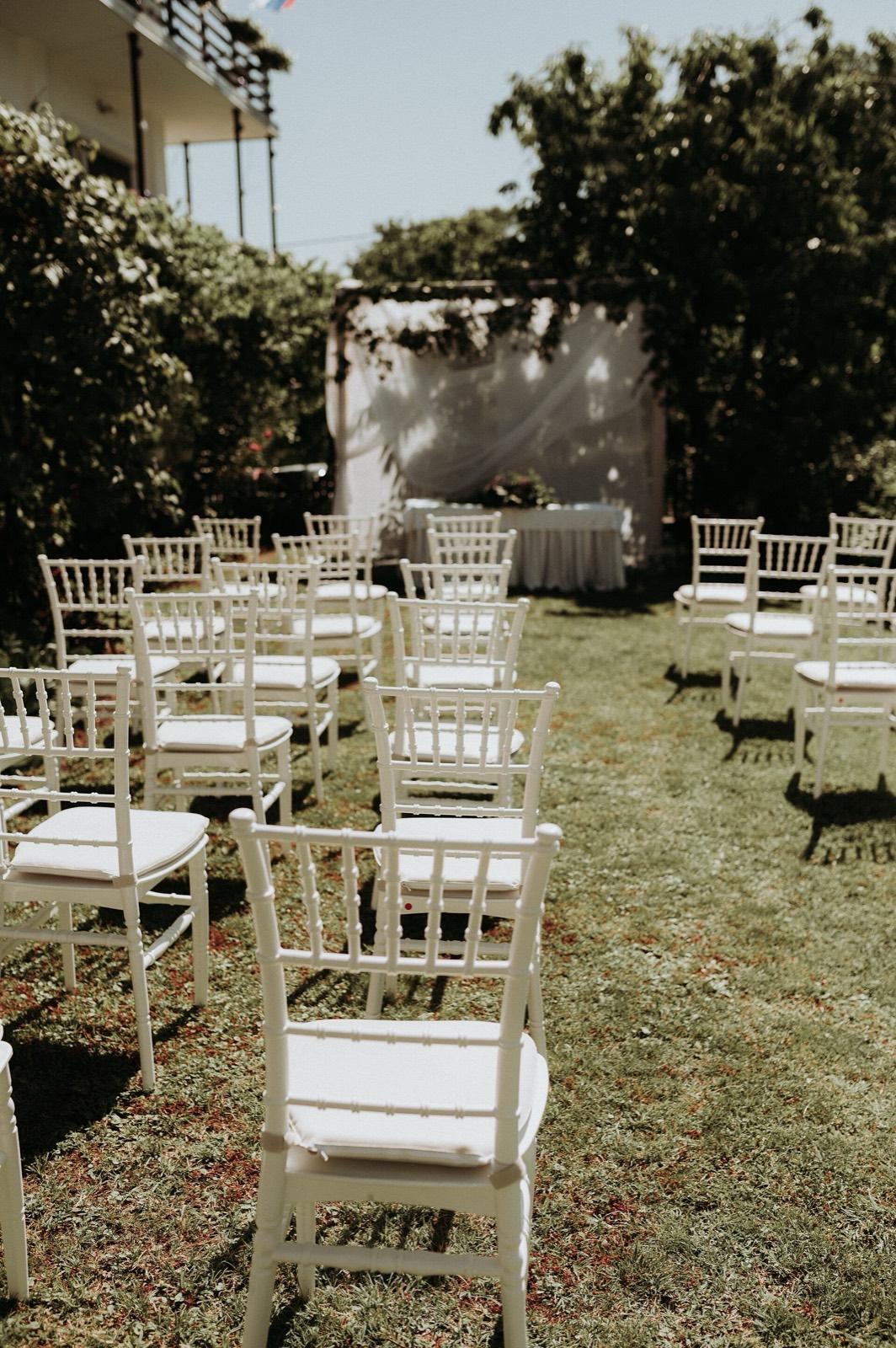 White chairs set out on a lawn for an outdoor ceremony
